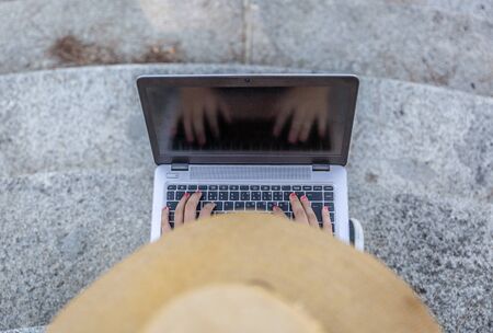 View from above of a girl with a hat working with her laptop outdoors. Lifestyle conceptの写真素材