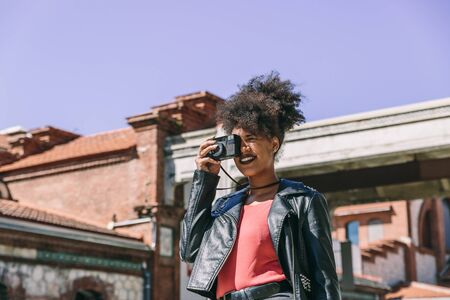 Attractive brunette tourist woman with afro hair prepares smiling to take a picture with her old...
