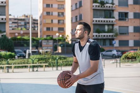Athletic body sportsman prepares to throw a shot with his basketball ball on an outdoor city courtの写真素材