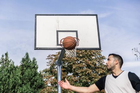Urban basketball player throws the ball into the air while on his back, to the board and the basket...