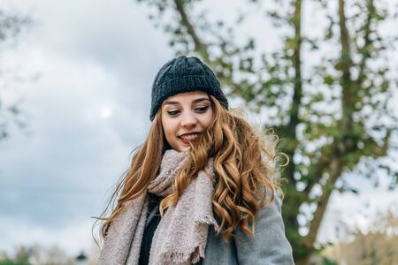 Portrait of a beautiful smiling caucasian blonde girl, in the middle of nature on a cold autumn dayの写真素材