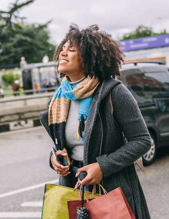 Afro-haired woman smiles very happily down the street a cold dayの写真素材