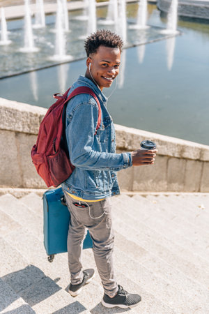 Happy brunette boy with afro hair smiles looking at his mobile phone