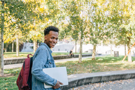 Happy man writes on his laptop in a nice park sitting near a green areaの写真素材