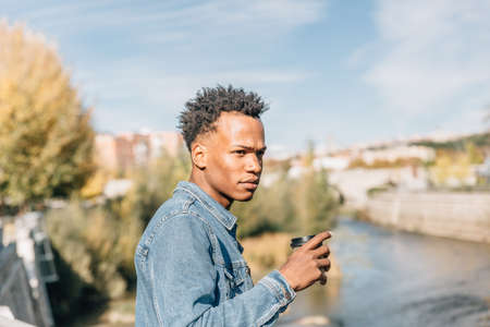 Afro hair man drinks a coffee relaxing in a park in a summer dayの写真素材