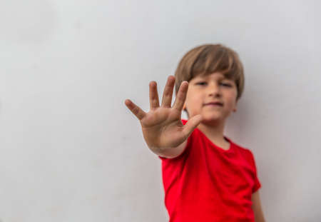 Close-up of the hand of a child giving all five with a white wall in the backgroundの写真素材