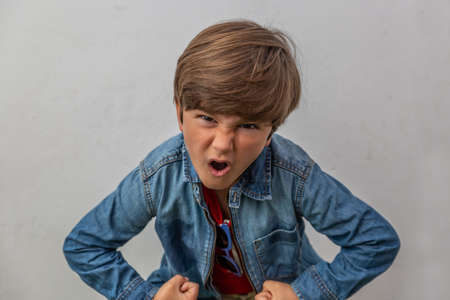 Close-up of very angry boy dressed in blue jacket with white backgroundの写真素材