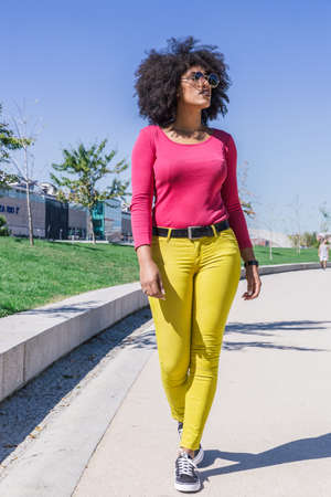 Attractive racial woman in yellow pants walks with a carefree airの写真素材
