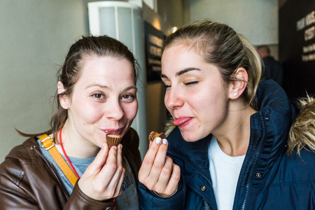 Two girls trying swiss chcolate at a choclate factory tasting tourの写真素材