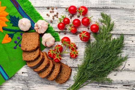 Still life on wooden background: tomatoes, black bread, garlic, fennel, bayberry pepperの写真素材