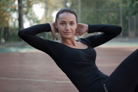 Young pretty fitness woman exercises during morning sport training workout on playground outdoorの写真素材