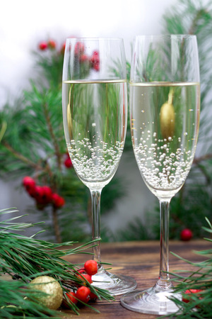 Christmas and New Year seasonal composition with pine tree branches, two glasses of champaign, golden balls ornament and red rowan berriesの写真素材