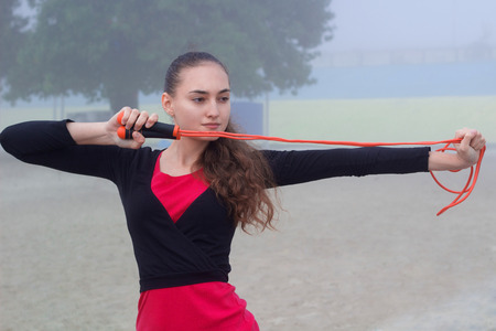 Young pretty slim fitness sporty woman doing streching exercise with rope during training workout outdoorの写真素材