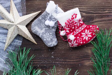 Christmas composition of two knitted socks and xmas tree branches and star ornament on wooden...