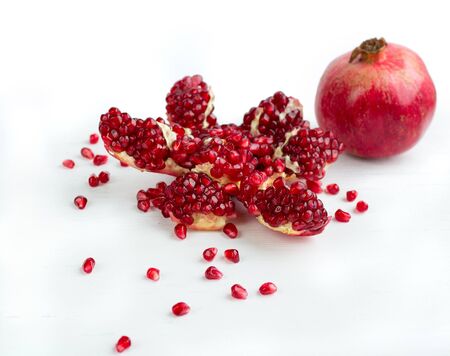 Cut-up dissected tasty garnet fruit pomegranate with rolled out seeds isolated on white backgroundの写真素材