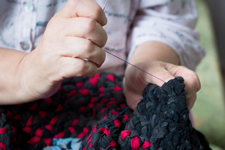 Close-up of elderly lady doing sewing hand work with needle and threadの写真素材