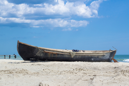 Small wooden fisher's boat with fishing nets drying on sandy beach near sealineの写真素材