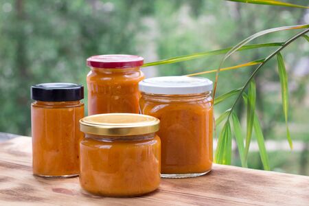 Summer composition of orange cans of apricot jam prepared from berry harvestの写真素材