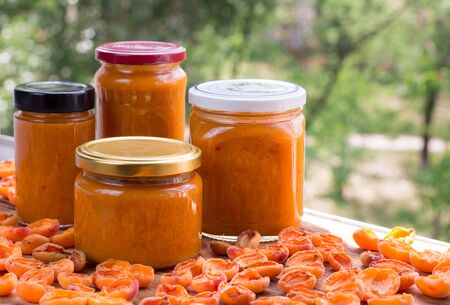 Orange cans of apricot jam prepared from summer harvest of melow berry fruitsの写真素材