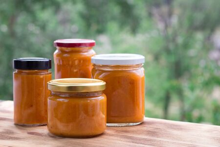 Summer composition of orange cans of apricot jam prepared from berry harvestの写真素材