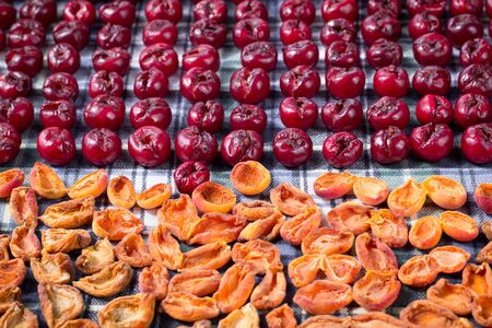Background pattern of fresh mellow cherry and apricot berries prepared for cooking and sun drying for conservation and preservationの写真素材