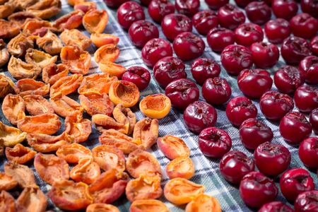 Background pattern of fresh mellow cherry and apricot berries prepared for cooking and sun drying for conservation and preservationの写真素材