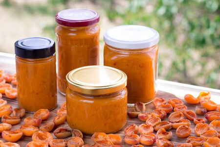 Orange cans of apricot jam prepared from summer harvest of melow berry fruitsの写真素材