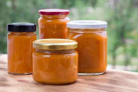 Summer composition of orange cans of apricot jam prepared from berry harvestの写真素材