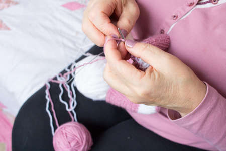 Process of yarn knitting by elderey woman: arms, spins, thread close up