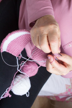 Process of yarn knitting by elderey woman: arms, spins, thread close up