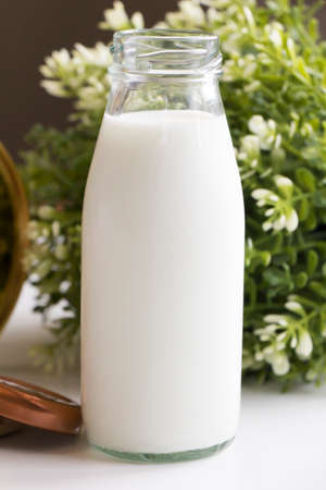 Fresh milk image in clear glass bottle on flower and leaf background.
Fresh milk for good...