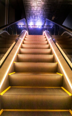 Upstairs escalator at night with lights