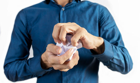 A man stands crumpling papers to show his dissatisfaction with his job.の写真素材