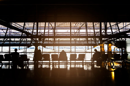 Waiting in the airport, backlit perspective, silhouettes of people waiting for travel at the airport, Travel and waiting for visitsの写真素材