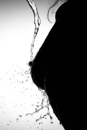 A silhouette of a woman s breast on which the water pours の写真素材