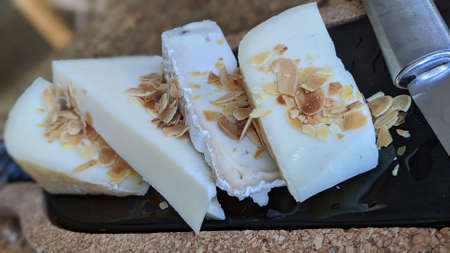 Cheese plate close-up. Wood and marble board with various cheese types and almonds on a wooden...