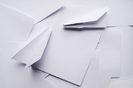 White paper planes on a background sheet of office paper. Origami