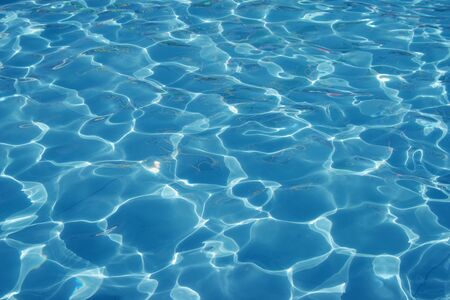 Blue romantic rippling water surface with sun glare.