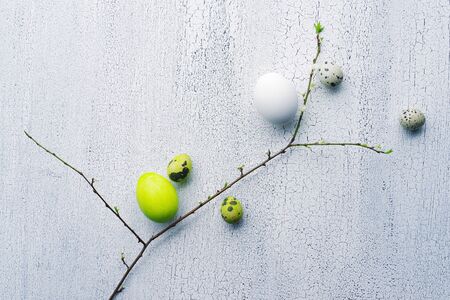 Easter bright colored eggs and decorative ornaments with green branches on a white vintage...