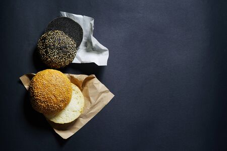 top view of two black and white burger rolls on a black background with sesame and flourの写真素材