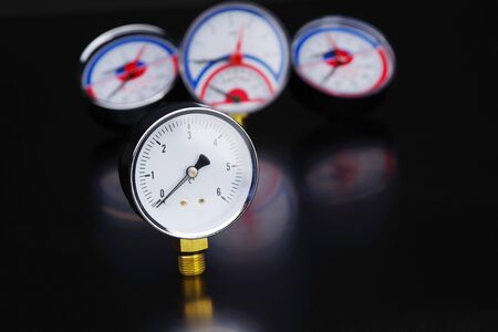 Dark surface with a deep reflection of pressure gauges.manometer in focus. A pressure gauge on the...
