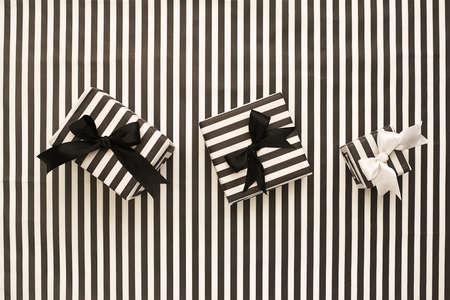 Striped black and white gift boxes on a striped background. The concept for greeting cards, invitations. Top view.の写真素材