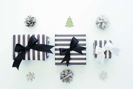 Striped black and white gift boxes, decorative snowflakes, Christmas trees and cones on a laconic...