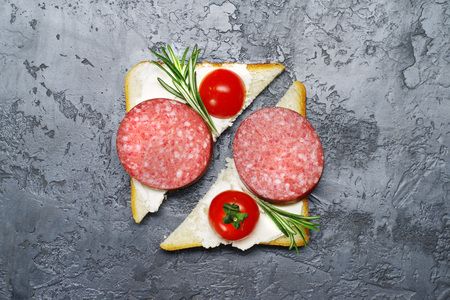 Top view of a fresh open sandwich with salami  on a gray concrete surface.の写真素材