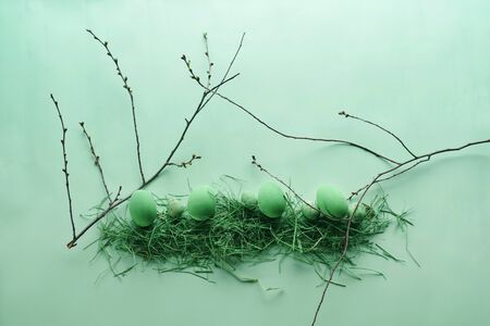 Painted Easter eggs in a decorative nest on a pastel green background. Easter concept in pastel colors. Top view. Flat lay. Punchy pastels.の写真素材