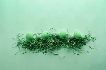 Painted Easter eggs in a decorative nest on a pastel green background. Easter concept in pastel colors. Top view. Flat lay. Punchy pastels.の写真素材