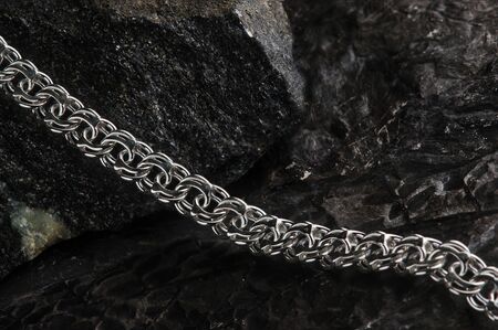 Silver jewelry chain on the background of wood, tree bark, close-up.Platinum, silver, decoration