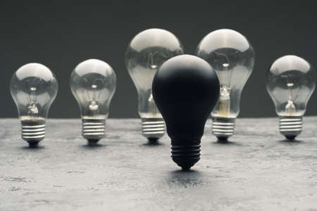 A few burned old bulbs and one black light bulb on a gray concrete background.の写真素材
