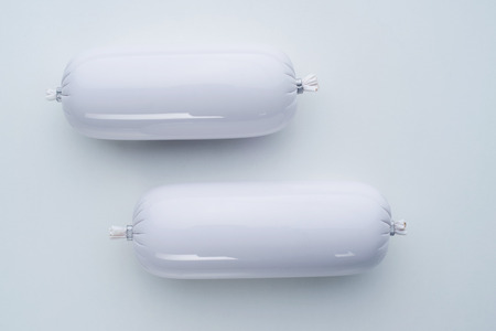Two sausages in a white shell on a white background. Template for advertising, catalog, poster.