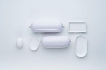 White food product in the form of sausage and white tableware on a white background. Top view. Flat...